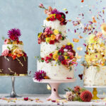 A photo of three floral-decorated cakes on stands, with petals flying off them - photography competition submission