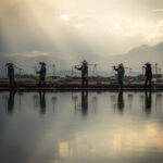 A photo of five people carrying harvested salt under the bright sun - photography competition submission